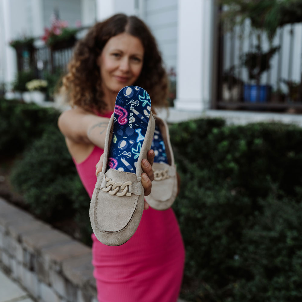 Woman holding up suede flat with Beach Bum print FLAT SOCKS inside #size_small-up-to-women-s-11-men-s-10