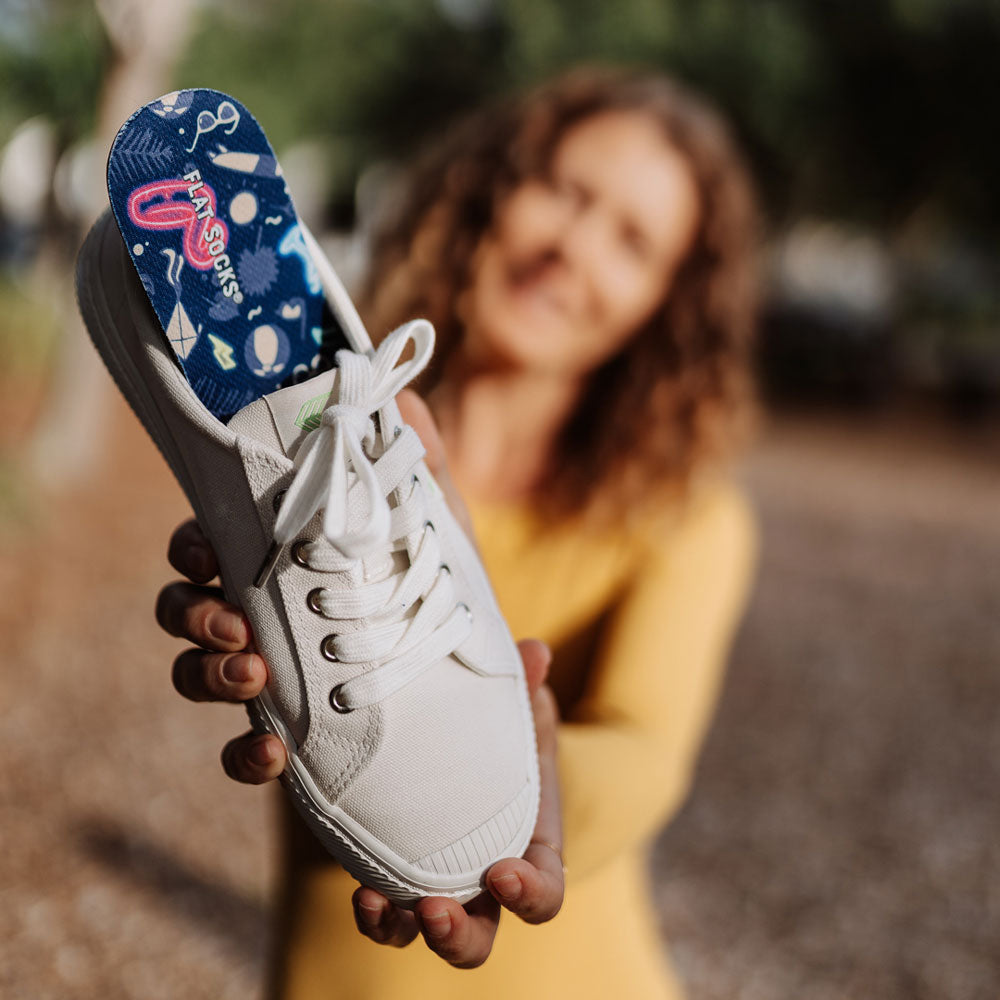 Woman holding up canvas shoe with Beach Bum print FLAT SOCKS inside #size_large-up-to-women-s-13-men-s-14