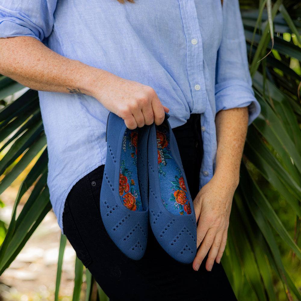 Woman standing in front of palm tree with blue flats and Blue Jean Baby FLAT SOCKS inside #size_small-up-to-women-s-11-men-s-10