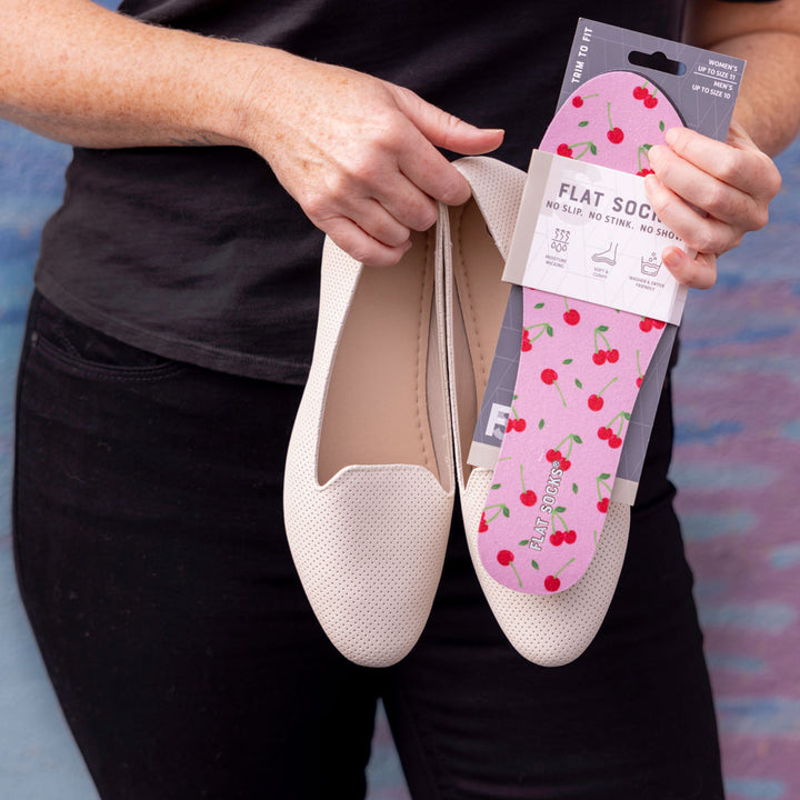 Woman holding up a package of Cherry Darling print FLAT SOCKS and cream colored flats #size_small-up-to-women-s-11-men-s-10