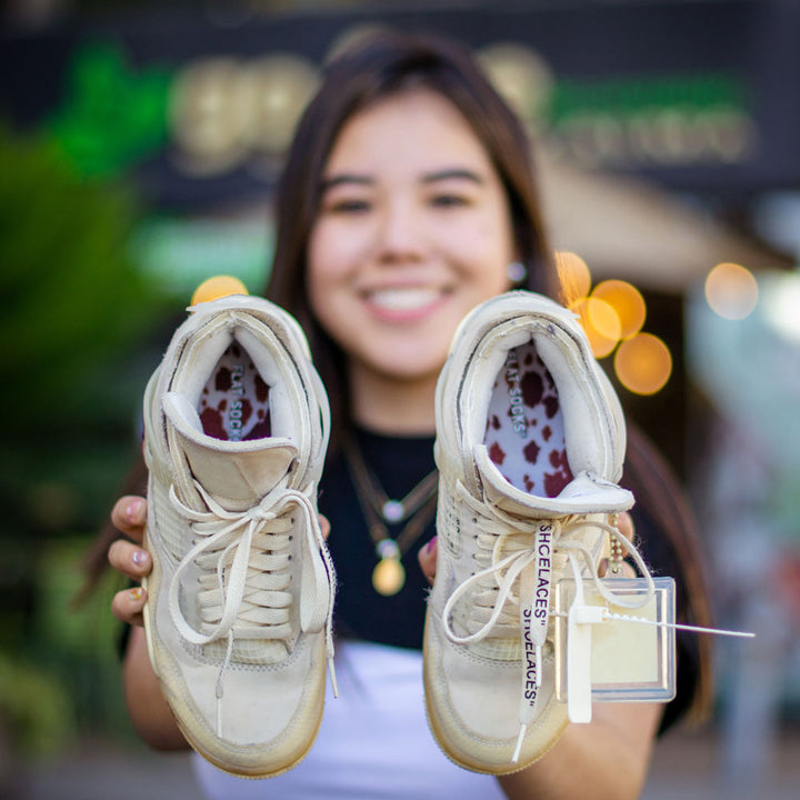 Girl holding up pair of tan sneakers with Brown Cow Print FLAT SOCKS inside #size_small-up-to-women-s-11-men-s-10