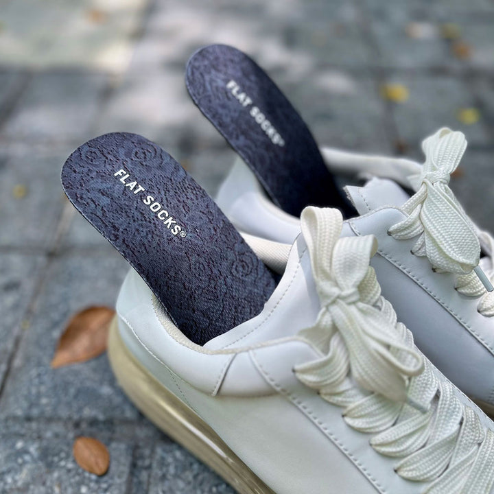 Pair of white sneakers sitting on sidewalk with dark lace FLAT SOCKS inside #size_small-up-to-women-s-11-men-s-10