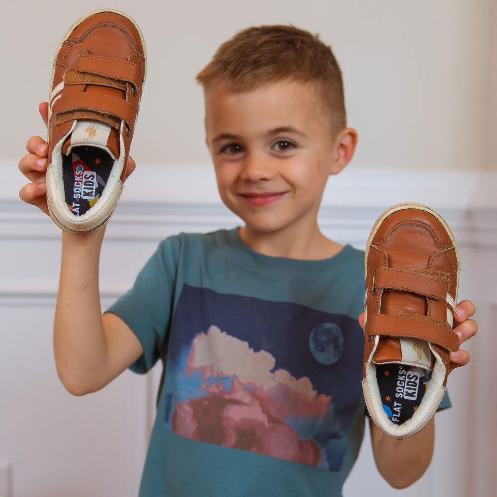 Little boy holding up a pair of dark tan hook and loop closed shoes with Outerspace FLAT SOCKS Kids inside #size_8-toddler-to-4-kid-s