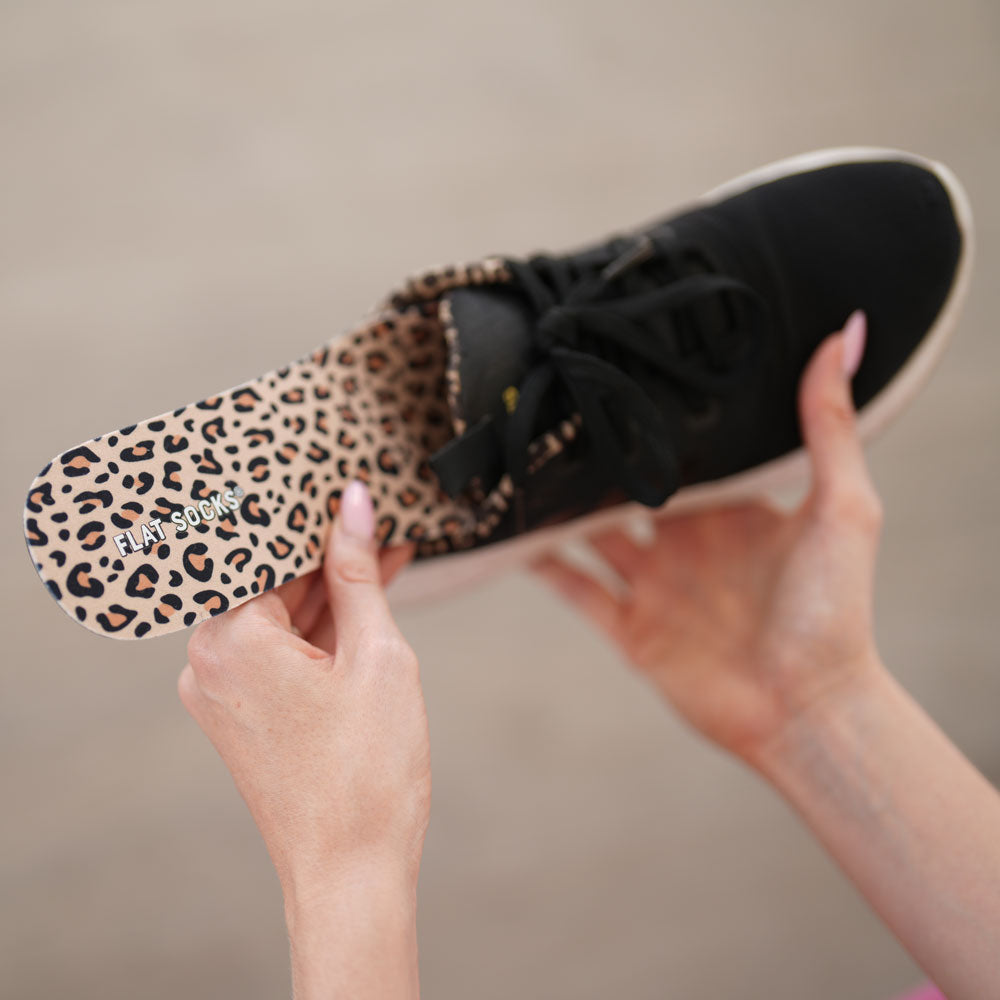 Woman placing Leopard FLAT SOCKS into black sneaker #size_large-up-to-women-s-13-men-s-14