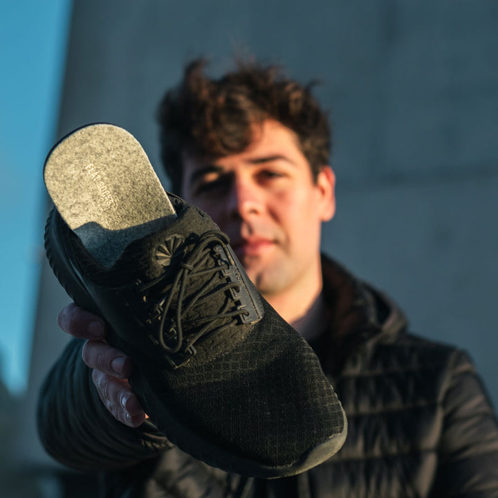 Man holding up a black tennis shoe with Light Heather Gray FLAT SOCKS inside #size_large-up-to-women-s-13-men-s-14