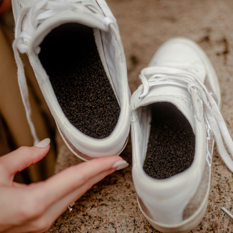 Woman holding up pair of white tennis shoes with Black Poodle FLAT SOCKS inside #size_small-up-to-women-s-11-men-s-10