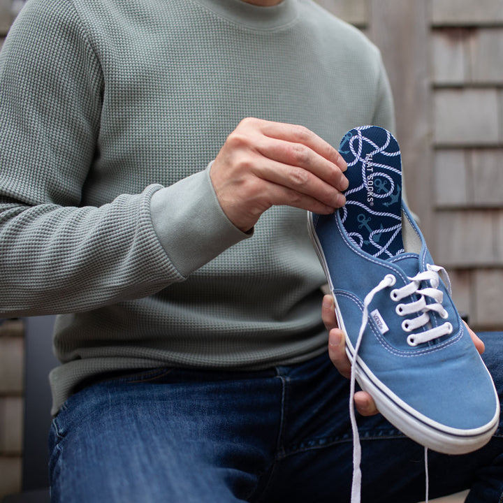 Man holding up blue canvas shoe with Seas-the-Day FLAT SOCKS inside #size_large-up-to-women-s-13-men-s-14