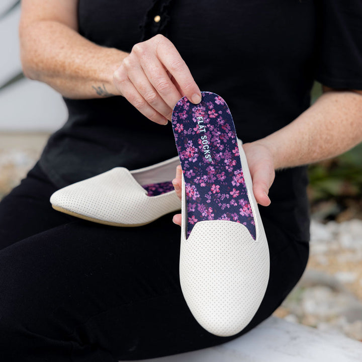 Woman placing Violet Thatcher FLAT SOCKS into cream-white slip-on flat shoe #size_large-up-to-women-s-13-men-s-14